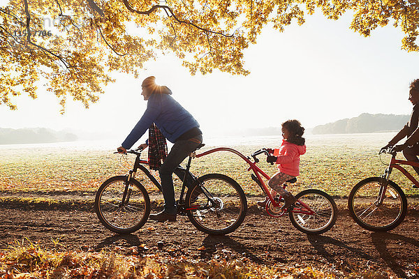 Vater und Tochter Radfahren mit Anhänger im sonnigen Herbstpark