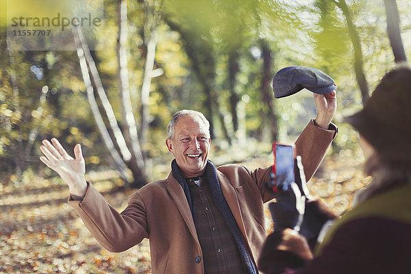 Senior Mann posiert für Frau mit Fotohandy im Herbstpark