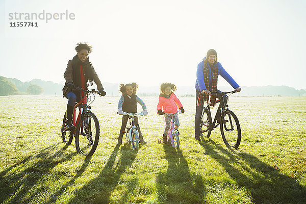 Portrait junges Familienradfahren im sonnigen Herbstparkgras