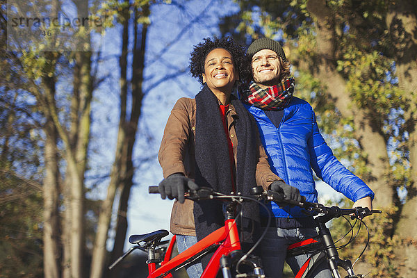 Lächelndes Paar mit Fahrrädern im sonnigen Herbstpark