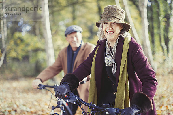 Lächelndes Seniorenpaar Radfahren im sonnigen Herbstwald