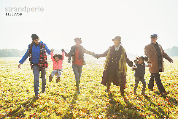 Verspieltes Mehrgenerationen-Familienwandern im sonnigen Herbstparkgras