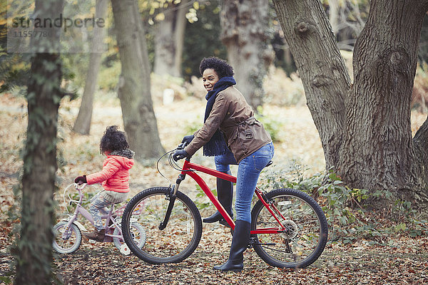 Mutter und Tochter Radfahren im Herbstwald