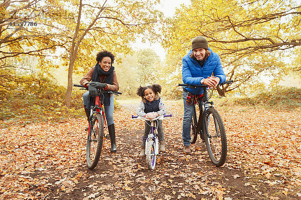 Portrait lächelndes junges Familienradfahren im Herbstpark