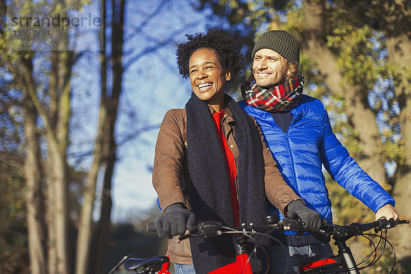 Lächelndes Paar Radfahren im sonnigen Herbstpark