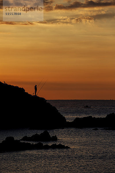 Spanien  Costa Brava  Blanes  einsamer Angler und Sa Palomera Felssilhouette bei Sonnenaufgang am Mittelmeer