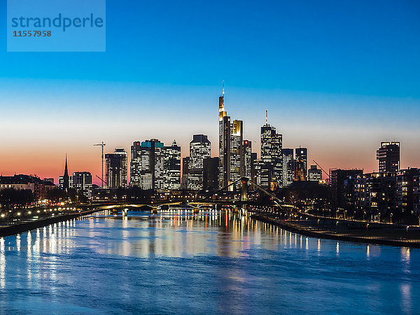 Deutschland  Frankfurt  Blick auf die Skyline mit Flößerbrücke und Main im Vordergrund bei Dämmerung