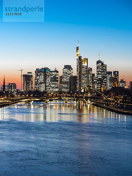 Deutschland  Frankfurt  Blick auf die Skyline mit Flößerbrücke und Main im Vordergrund bei Dämmerung