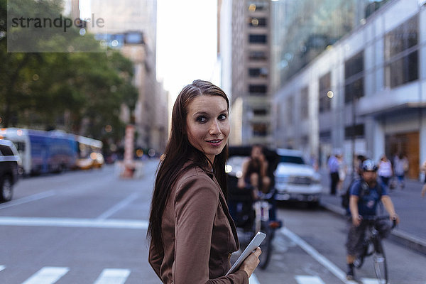 USA  New York  Manhattan  Portrait einer jungen Geschäftsfrau mit Tablette über die Straße