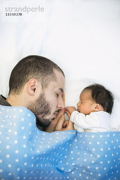 Vater schläft neben seinem neugeborenen Mädchen.