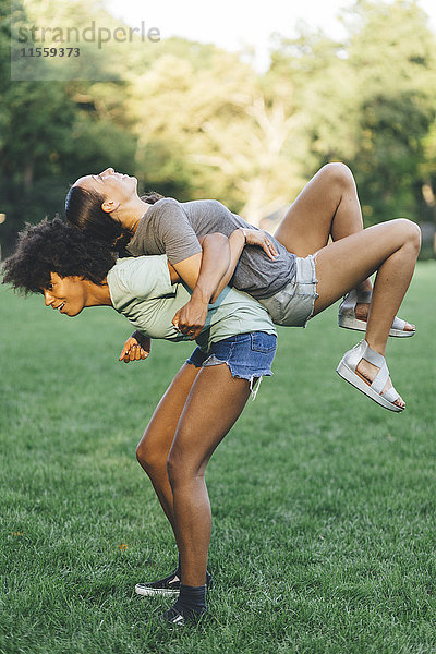 Junge Frau mit ihrem besten Freund Huckepack im Park