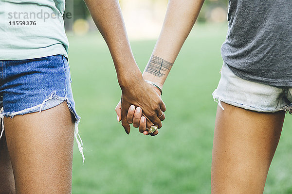 Zwei Frauen  die sich in einem Park an den Händen halten.