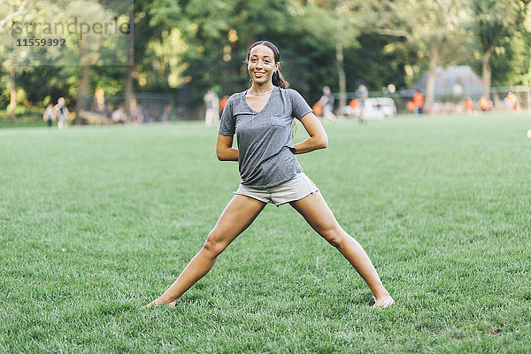 Lächelnde junge Frau beim Yoga im Park