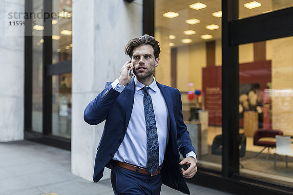 Handsone Geschäftsmann in Eile läuft durch Manhattan  mit Smartphone