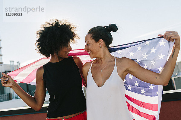 Freundinnen mit US-amerikanischer Flagge  auf dem Dach stehend