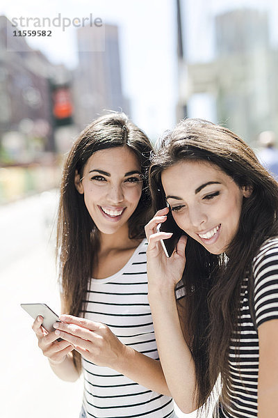 USA  New York City  zwei glückliche Zwillingsschwestern mit Mobiltelefonen in Manhattan