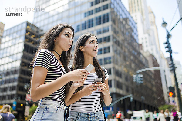 USA  New York City  zwei Zwillingsschwestern mit Mobiltelefonen in Manhattan
