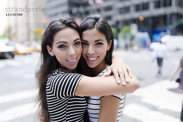 USA  New York City  Portrait von zwei schönen Zwillingsschwestern in Manhattan umarmend