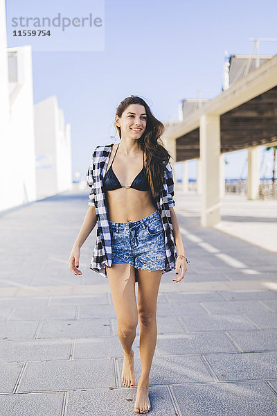 Junge hübsche Frau in Strandkleidung  auf der Straße spazieren gehen