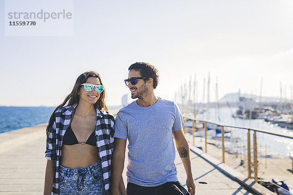 Glückliches junges Paar beim Spaziergang am Hafen