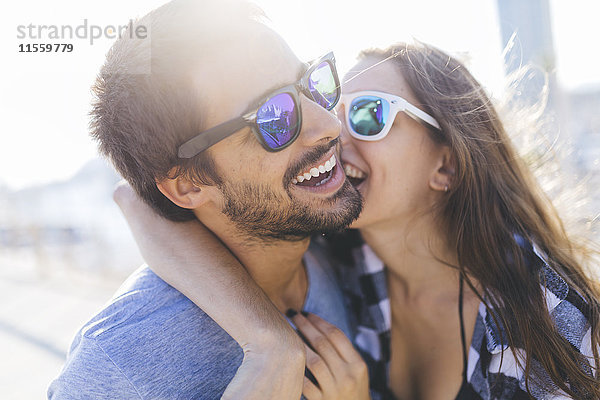 Ein glückliches junges Paar  das am Hafen spazieren geht und sich küsst.