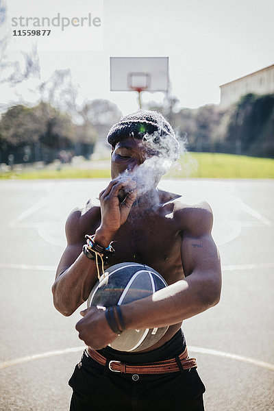 Barechested Basketballspieler auf dem Platz Rauchen ein Joint