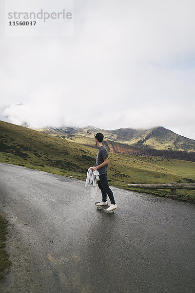 Spanien  Lleida  junger Mann auf Skateboard in ländlicher Landschaft