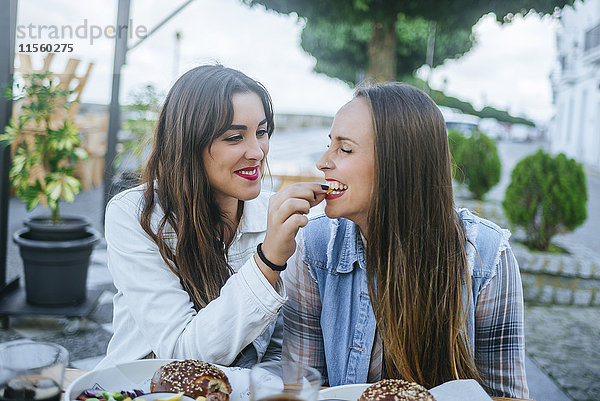 Junge Frau füttert ihren Freund in einem Straßenrestaurant