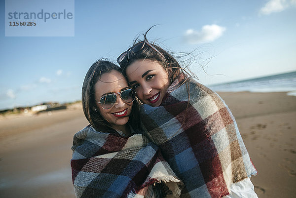 Porträt von zwei Frauen mit Decke am Strand