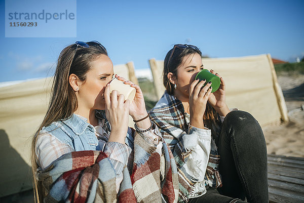 Zwei junge Frauen beim Kaffeetrinken am Strand