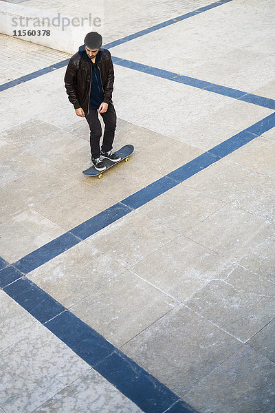 Junger Mann beim Skateboardfahren auf einem Platz