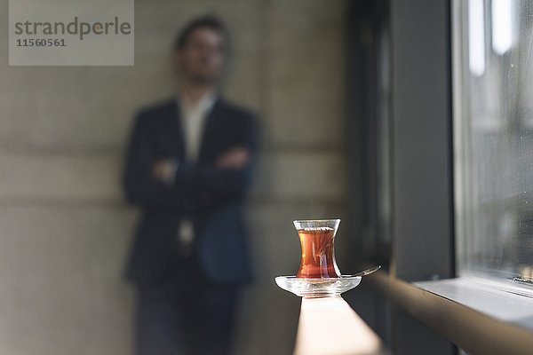Glas türkischer Tee am Fenster mit Geschäftsmann im Hintergrund