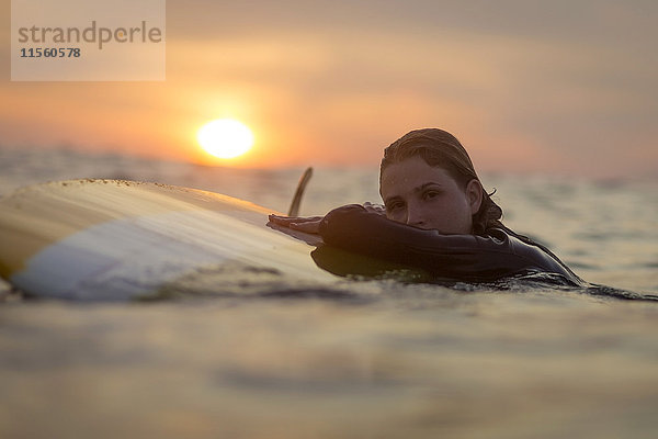 Indonesien  Bali  Portrait einer Surferin im Meer bei Sonnenuntergang
