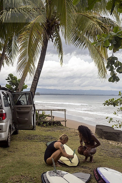 Indonesien  Java  zwei Frauen bei der Vorbereitung des Surfboards an der Küste