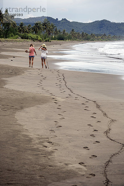 Indonesien  Java  Rückansicht von zwei Frauen  die am Strand spazieren gehen