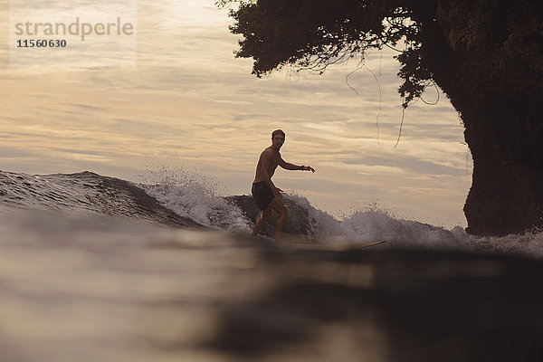 Indonesien  Java  Mann beim Surfen bei Sonnenuntergang