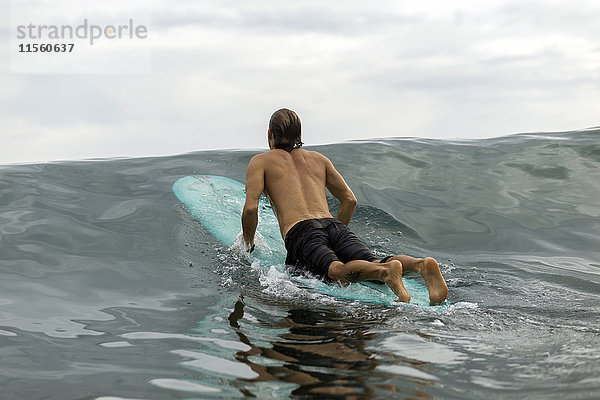 Indonesien  Java  Mann auf dem Surfbrett auf dem Meer liegend