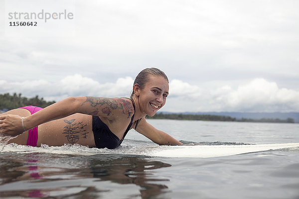 Indonesien  Java  lächelnde Frau auf dem Surfbrett auf dem Meer liegend