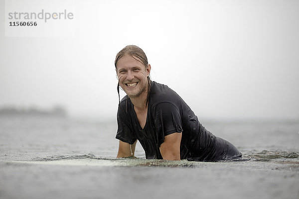 Indonesien  Java  lächelnder Mann auf dem Surfbrett auf dem Meer