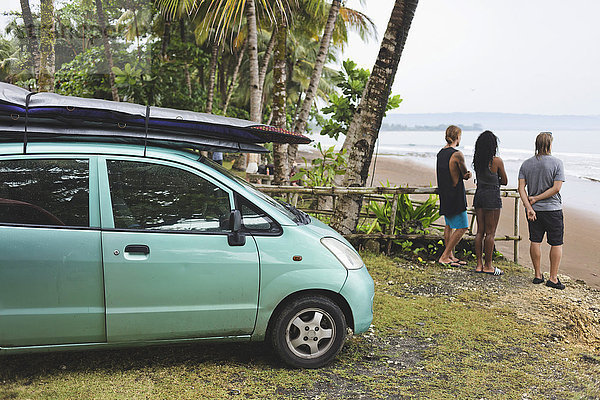 Indonesien  Java  Freunde stehen an der Küste neben dem Auto mit Surfbrettern