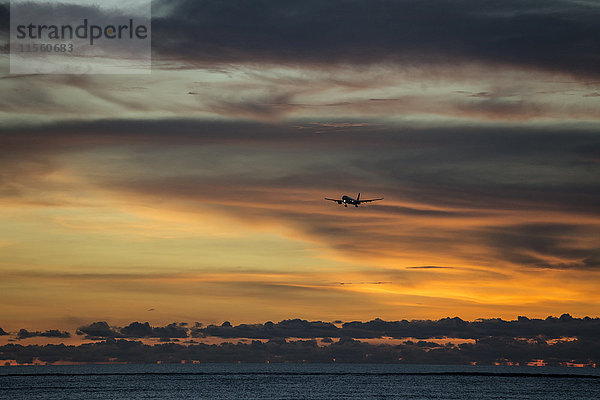 Indonesien  Bali  Flugzeug am Himmel und Sonnenuntergang über dem Meer