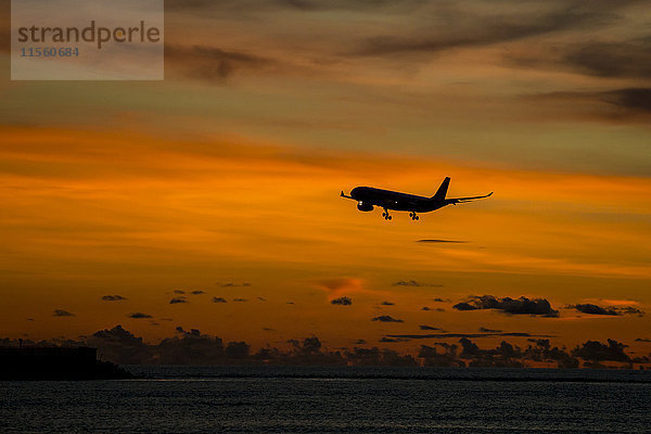 Indonesien  Bali  Flugzeug am Himmel und Sonnenuntergang über dem Meer