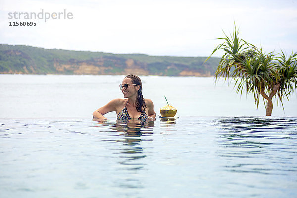 Indonesien  Insel Lombok  lächelnde Frau im unendlichen Pool