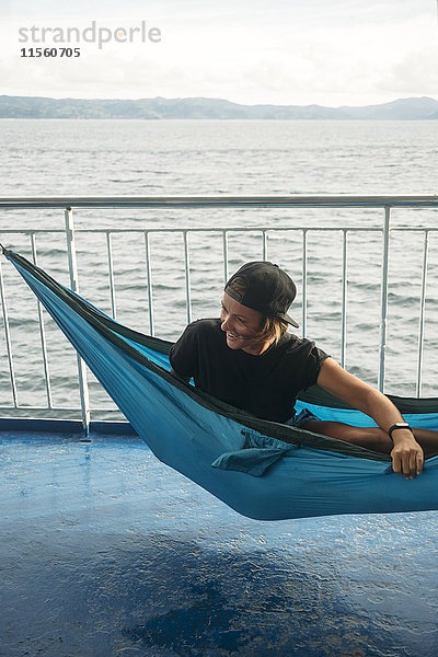 Indonesien  Insel Lombok  lächelnde Frau in Hängematte auf Schiffsdeck