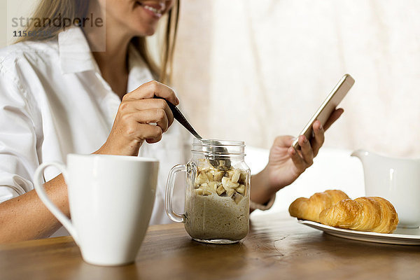 Frau am Frühstückstisch mit dem Handy