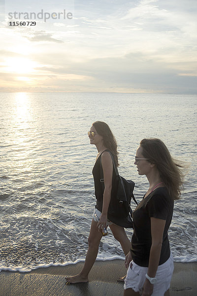 Indonesien  Bali  zwei Frauen am Strand bei Sonnenuntergang