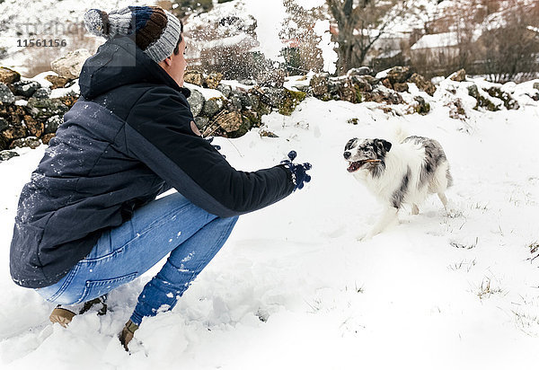 Junger Mann spielt mit seinem Hund im Schnee
