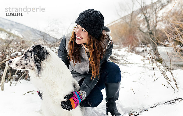 Junge Frau spielt mit ihrem Hund im Schnee