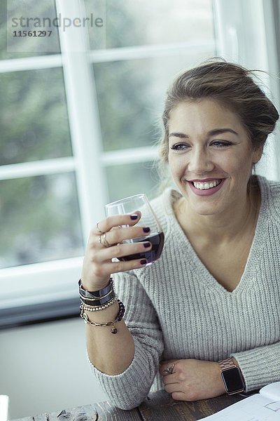 Porträt einer lächelnden jungen Frau mit einem Glas Kaffee