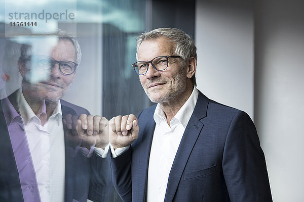 Zuversichtlicher Geschäftsmann schaut aus dem Fenster